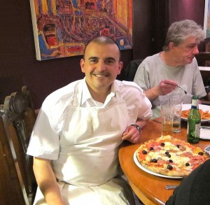 Italian man in chef's whites smiling at dinner table