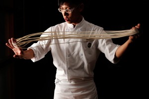 Bespectacled Asian man making noodles