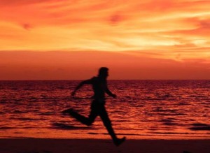 A man running down a beach during a red sunset